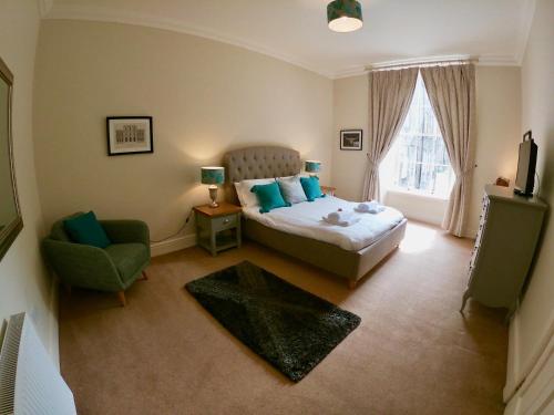 a bedroom with a bed and a chair and a window at Escape To Edinburgh @ Broughton Place in Edinburgh