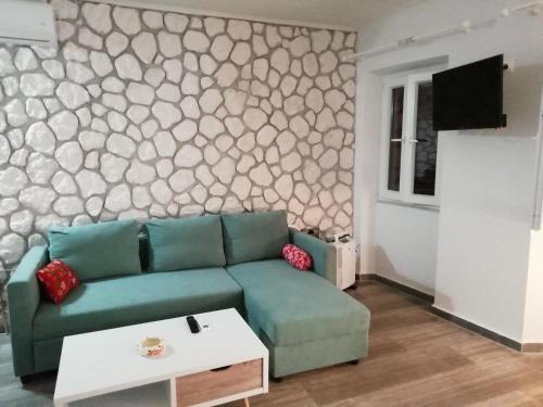 un soggiorno con divano verde e parete in pietra di C & A House a Città di Corfù