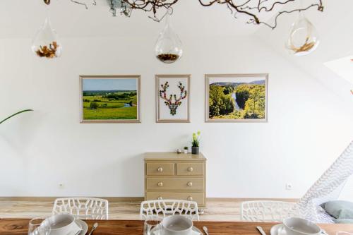 a dining room with white furniture and pictures on the wall at Zythogite Appartement 6 personnes avec jardin, bbq in Tintigny