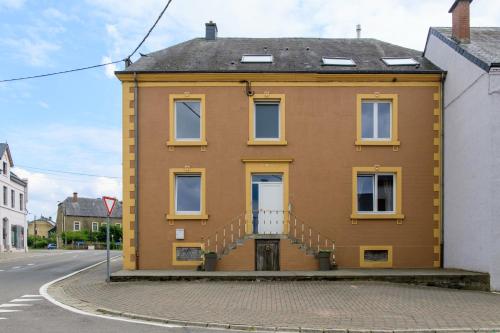 a yellow house with stairs on a street at Zythogite Appartement 6 personnes avec jardin, bbq in Tintigny