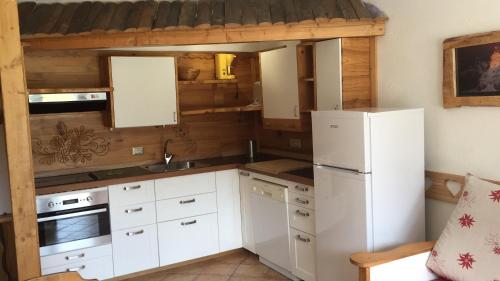 een keuken met witte kasten en een witte koelkast bij Piolet Panoramic Apartments in Breuil-Cervinia