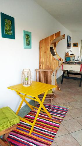 a yellow picnic table in a room with a piano at Ô PasSage - Kaz Auberge in Saint-Pierre