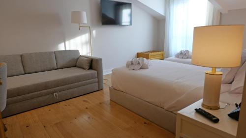 a living room with a bed and a couch at Casa dos Ofícios Hotel in Tomar