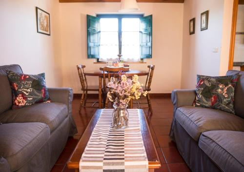 una sala de estar con 2 sofás y una mesa con flores en Casa Rural Camangu, en Camango