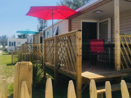 a wooden deck with a red umbrella on a house at Domaine MON CALME in Piriac-sur-Mer