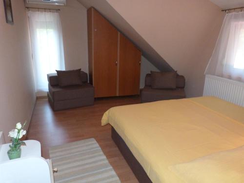 a bedroom with a bed and two chairs and a staircase at Andi Apartman in Gyula