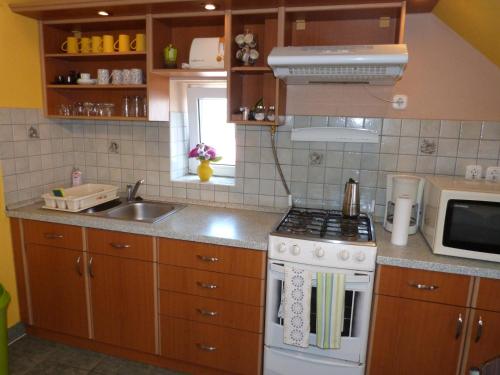 a kitchen with a stove and a sink and a microwave at Andi Apartman in Gyula