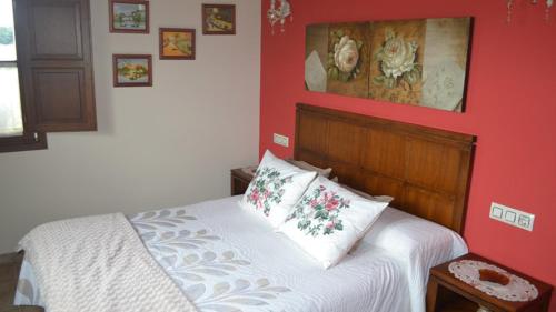 a bedroom with a bed with a red wall at El Rincón del Oteru in Llanes