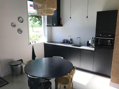 een keuken met een zwarte tafel en een wastafel bij Guesthouse de Bovenboer in Nijeveen