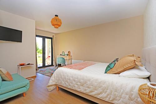 a bedroom with a bed and a chair and a television at L Esprit du Clain chambres d hôtes BandB de standing proches du Futuroscope Golf et Lac de St Cyr in Naintré