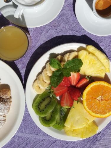 a plate of fruit on a table with a cup of coffee at Hotel Belvir in Villasimius