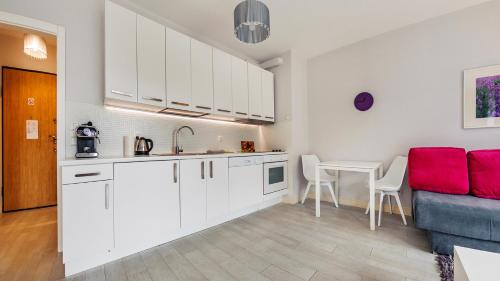 a kitchen with white cabinets and a table and a couch at Sopot Residence - Sea Deluxe in Sopot