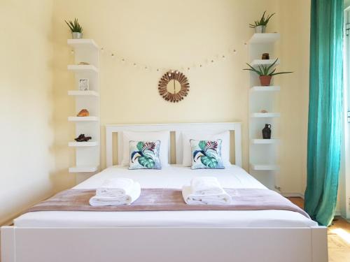 a bedroom with a large white bed with towels on it at Green Element Guesthouse in Costa da Caparica