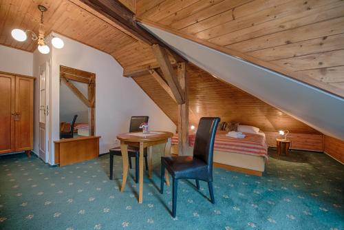 a bedroom with a bed and a table and a bed and a staircase at Hotel Zlatý Orel in Ostravice