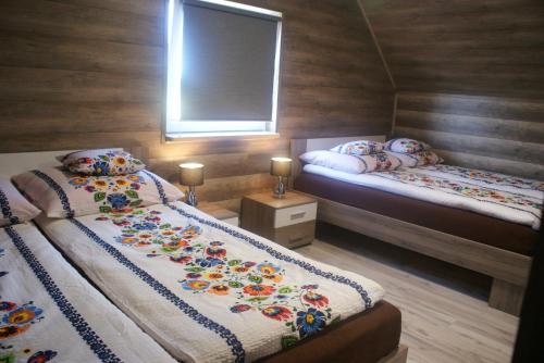 two beds in a room with wooden walls at Agrodomki Okej-Biały Dom in Gardna Wielka