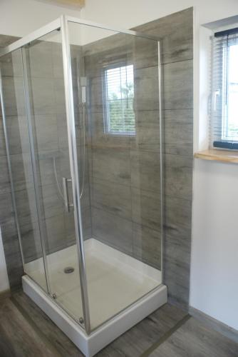 een douche met een glazen omhulsel in een badkamer bij Agrodomki Okej-Biały Dom in Gardna Wielka