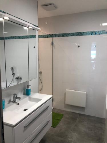 a white bathroom with a sink and a shower at Rezeda Apartman in Fonyód