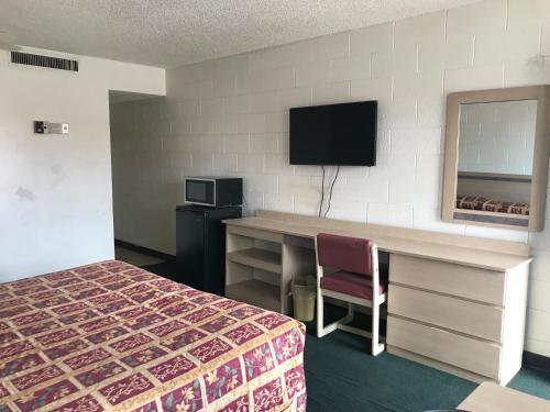 um quarto de hotel com uma cama, uma secretária e uma televisão em Super Lodge Motel El Paso em El Paso