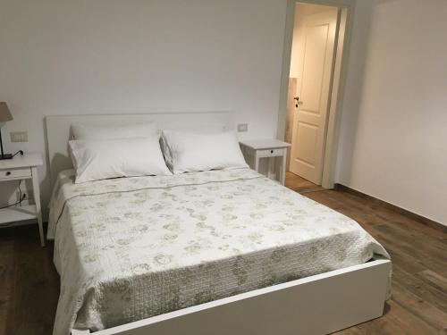 - un lit blanc dans une chambre blanche avec deux tables dans l'établissement L’Acerba B&B, à Ascoli Piceno