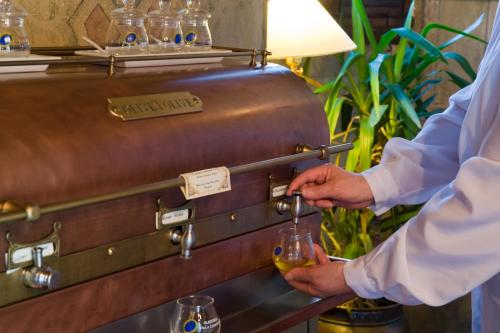 a man holding a glass of wine in front of a suit case at Villa Campestri Olive Oil Resort in Vicchio