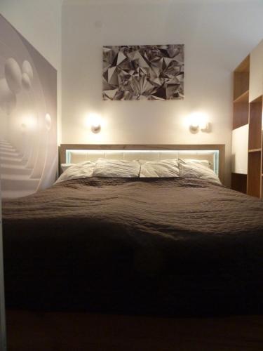 a bedroom with a bed and a painting on the wall at ROSE Apartman in Debrecen