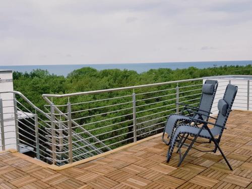 two chairs sitting on a deck with a view at Apartament Piasek i Morze in Rowy