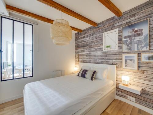 une chambre avec un lit blanc et un mur en bois dans l'établissement Escale Pamatxi : Vieux port, à La Rochelle