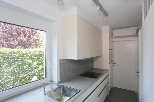 a kitchen with white cabinets and a sink and a window at Appartementhaus Franz Samonig in Drobollach am Faakersee