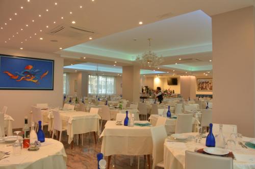 un salón de banquetes con mesas blancas y sillas blancas en Hotel Altis, en San Benedetto del Tronto