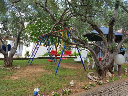 eine Schaukel in einem Park mit zwei Bäumen in der Unterkunft Apartmani Maver in Sveti Filip i Jakov