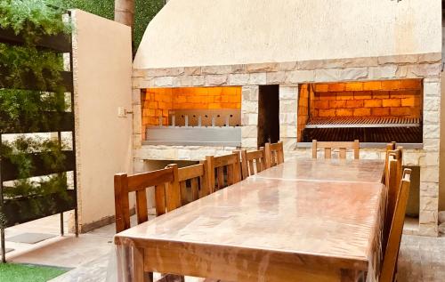 una mesa de madera con sillas y una chimenea de piedra en Del Rio Apart Hotel, en Encarnación