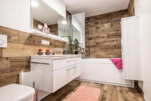 a bathroom with white cabinets and a wooden wall at Moderne Souterrain-Wohnung in Anif