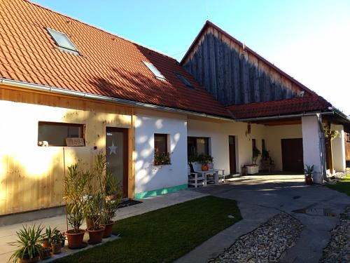 a white house with a red roof and some plants at Vidiecky apartmán Kubo in Pavčina Lehota