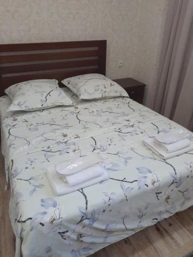 a bed with white sheets and blue flowers on it at Apartments on Akhalubani St 2 in Tbilisi City