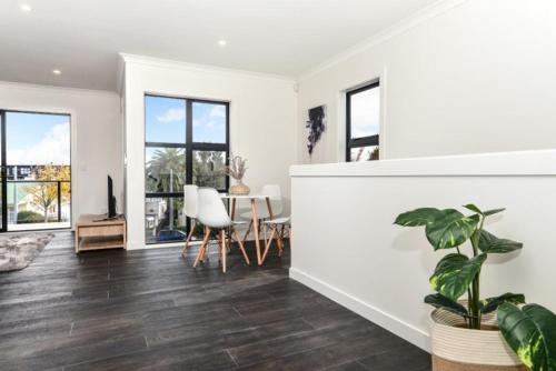 a living room with white walls and a table with a plant at Central Park Gemini Apartments in Hamilton