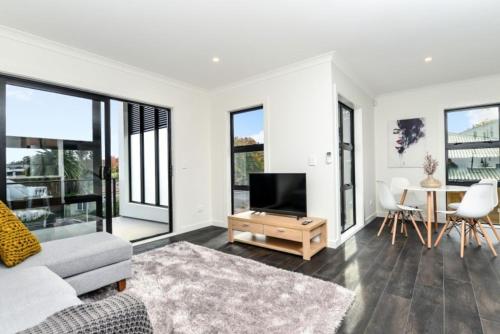a living room with a television and a table with chairs at Central Park Gemini Apartments in Hamilton