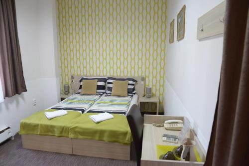 a small bedroom with a bed with a yellow wall at Guest House GOLDEN COIN in Niš