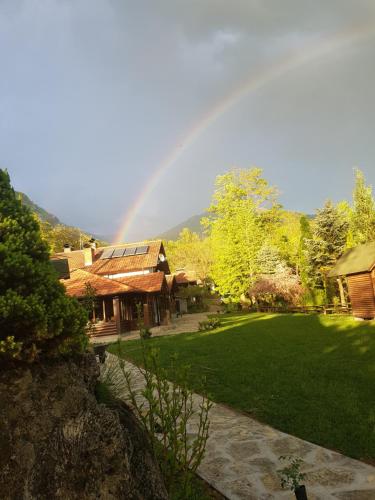 a rainbow over a house with a yard with a rainbow at Vodopad Lisine in Strmosten