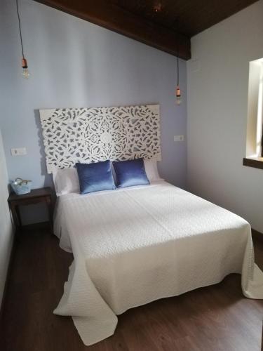 1 dormitorio con 1 cama blanca y 2 almohadas azules en Casa Rural El Enebro, en Navamorcuende