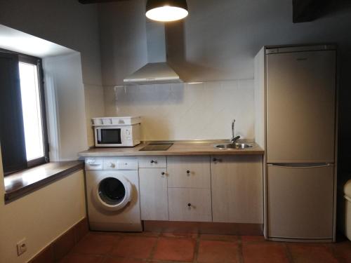 a kitchen with a washing machine and a microwave at Casa Rural El Enebro in Navamorcuende