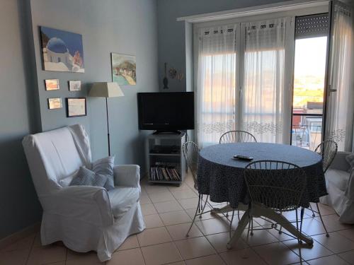ein Wohnzimmer mit einem Tisch, Stühlen und einem TV in der Unterkunft Appartamento Bellavista in Sanremo