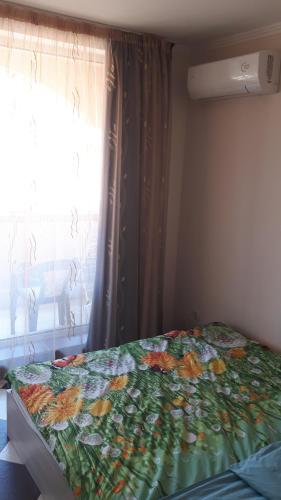 a bedroom with a bed with a flowered blanket and a window at Hacienda Beach Apartment mit Meerblick in Sozopol