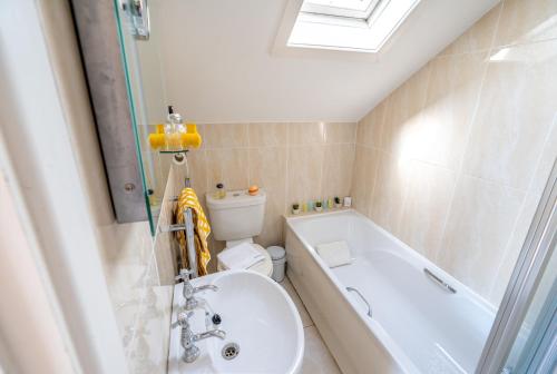 a bathroom with a toilet and a tub and a sink at Coral Gables Guesthouse & Campsite in Rosslare