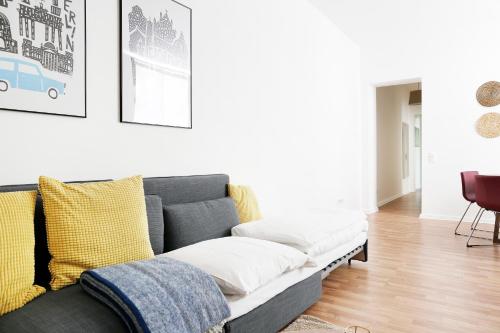 ein Wohnzimmer mit einem grauen Sofa und gelben Kissen in der Unterkunft Be in Berlin Apartments in Prenzlauer Berg in Berlin