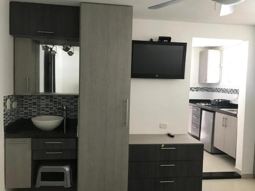 聖瑪爾塔的住宿－EDIFICIO PALANOA APTO 507PQ RODADERO，厨房配有黑色橱柜和墙上的电视。