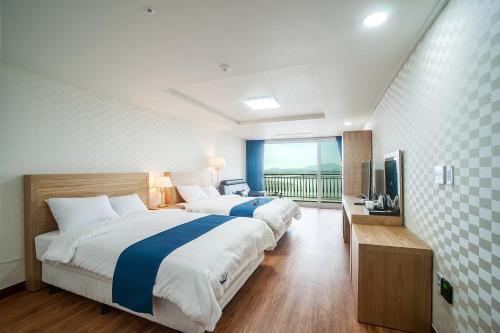 a hotel room with two beds and a television at Breeze Bay Hotel in Seogwipo