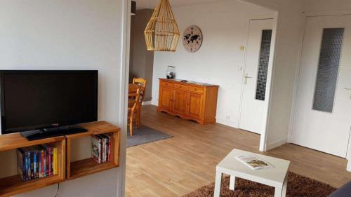 a living room with a flat screen tv and a table at UNE PAUSE SUR LA CÔTE in Boulogne-sur-Mer