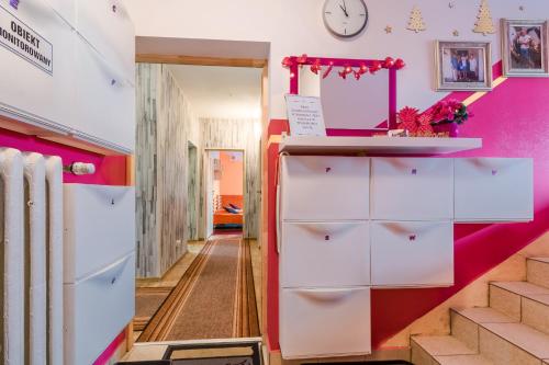 a hallway with pink and white cabinets and stairs at Pokoje Goscinne Oliwia & Laura I in Rumia