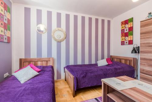 two beds in a room with purple sheets at Pokoje Goscinne Oliwia & Laura II in Rumia