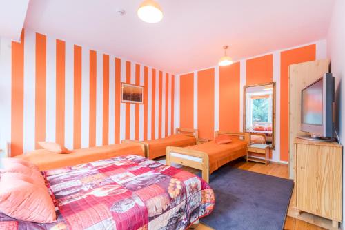 a bedroom with orange striped walls and a bed and a television at Pokoje Goscinne Oliwia & Laura II in Rumia